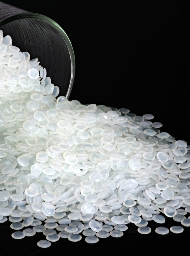 Industrial white plastic beads, granules on black background.