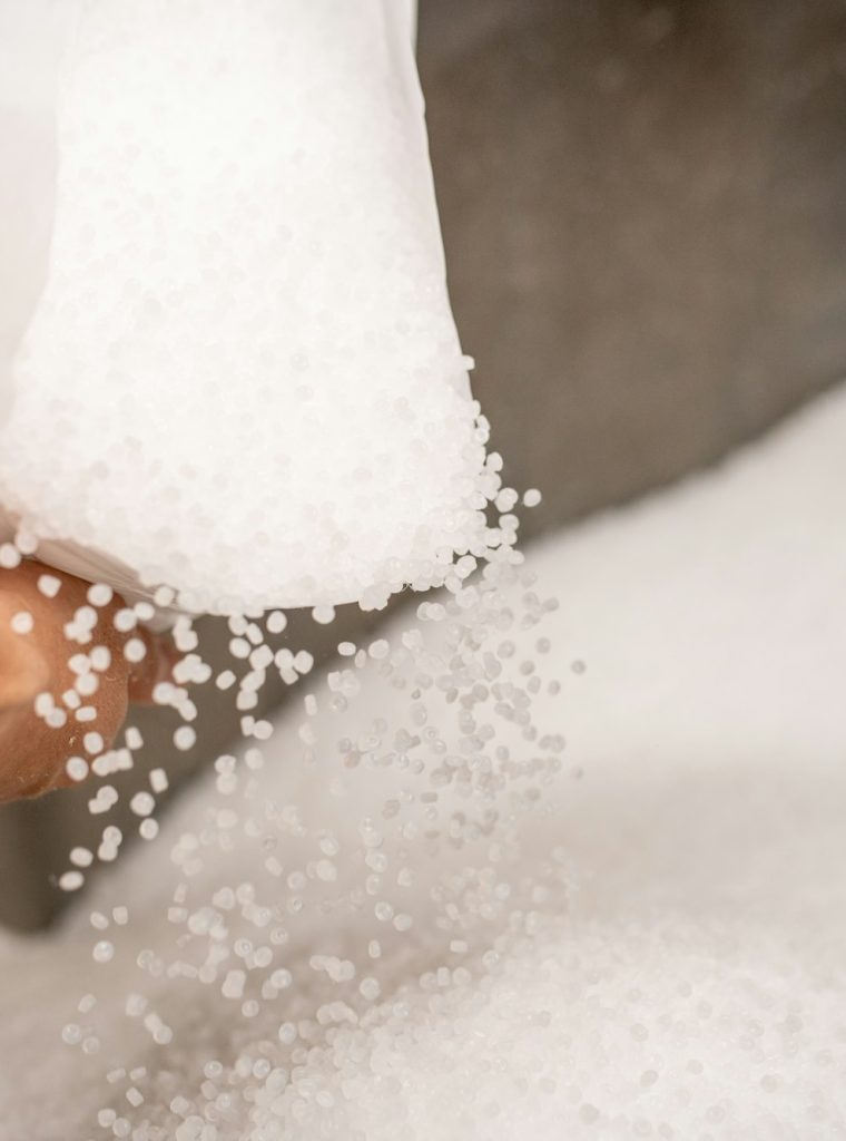 Small plastic granules scattering out of white sack held by worker Small plastic granules scattering out of white sack held by worker